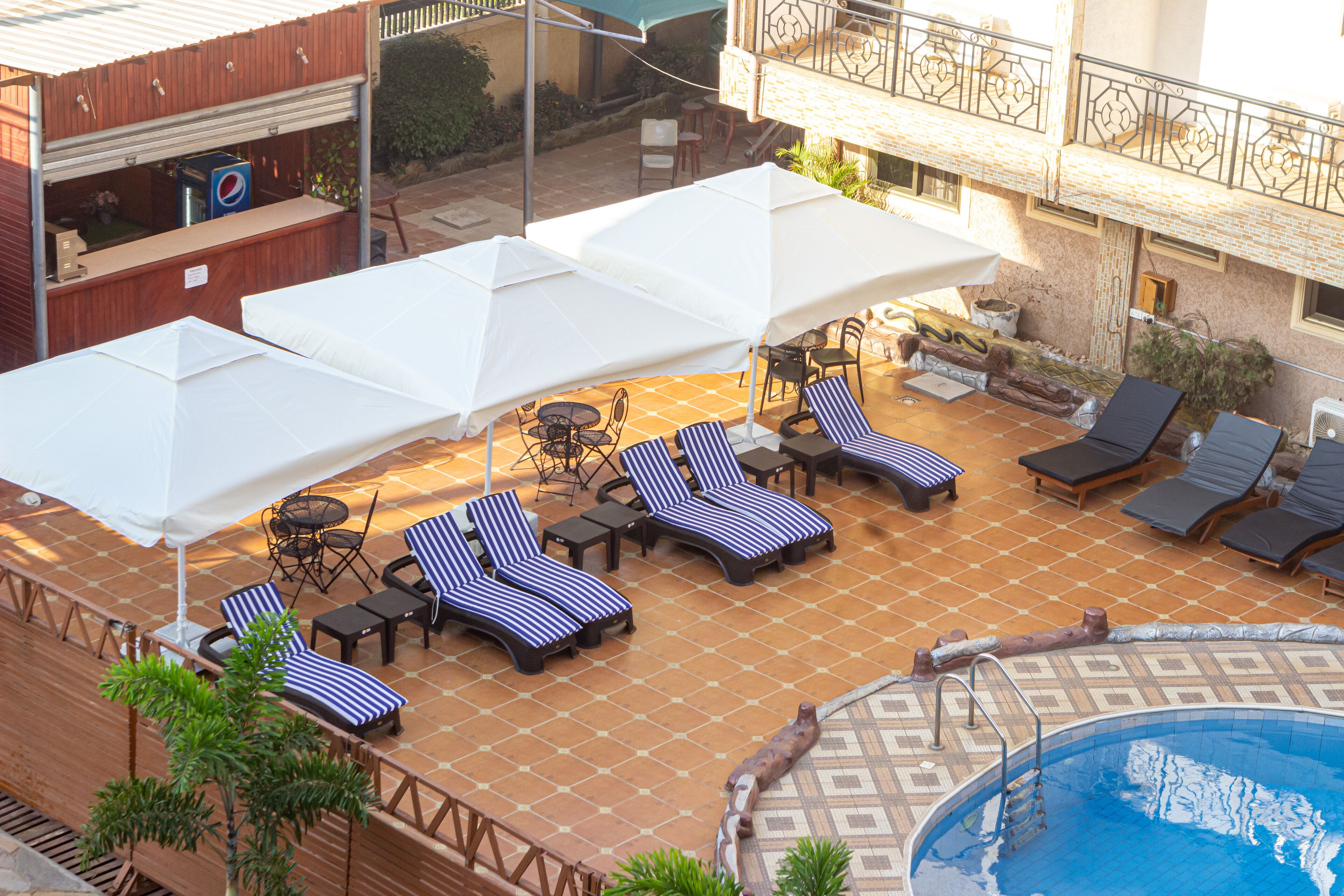 Un espace extérieur avec une piscine, des chaises longues et des parasols, ainsi qu’une petite piscine et un bar.