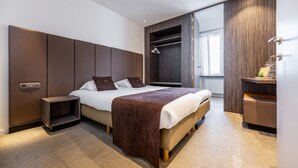 Un dormitorio moderno con una cama grande, armario empotrado y una mesita de noche pequeña.