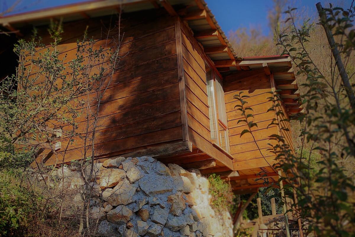 A rustic cabin with a stone foundation, wooden walls, and a sloped roof.