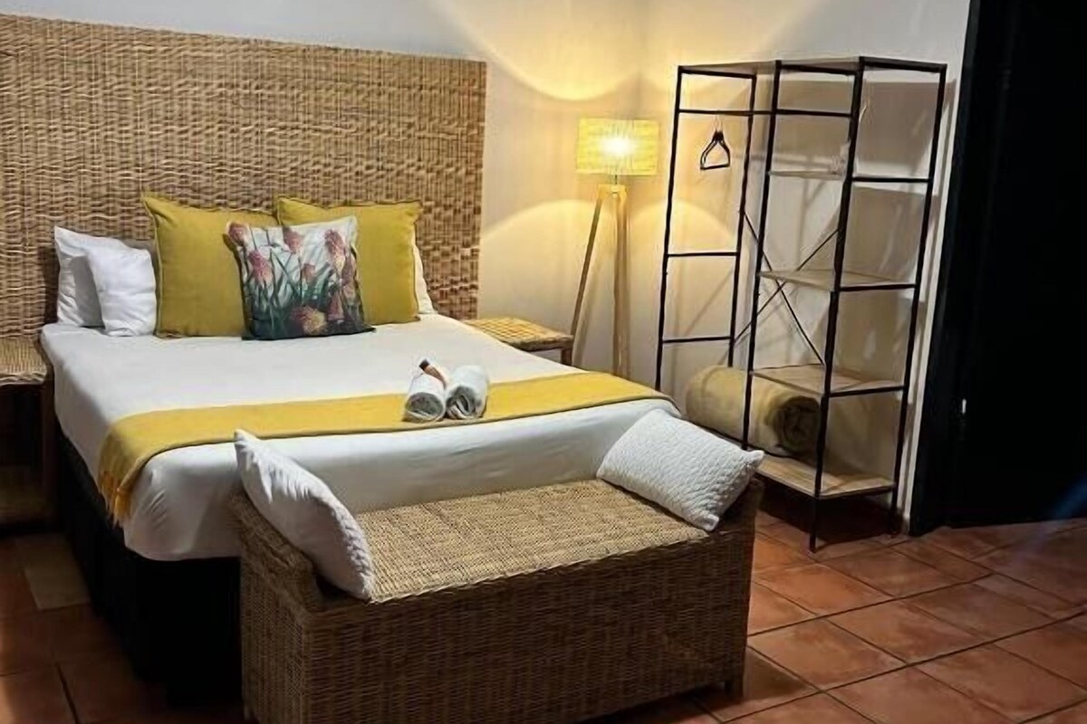 A hotel room with a large bed, a bedside table, a lamp, and a wardrobe.