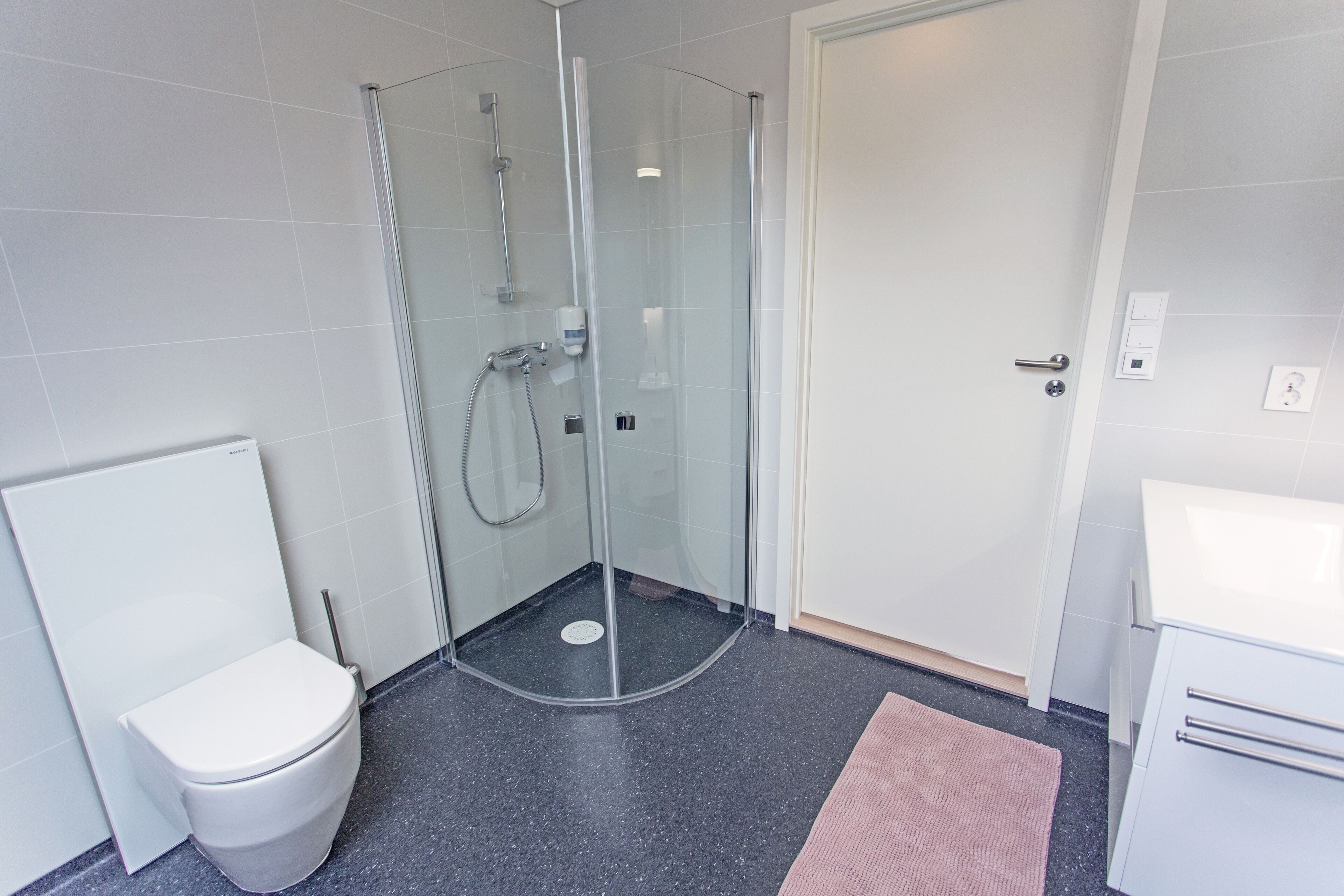 A modern bathroom with a glass-enclosed shower, a white toilet, and a white sink.