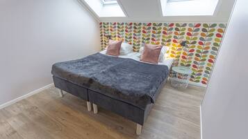 Un dormitorio con cama, mesita de noche, lámpara y ventana.