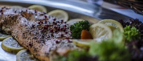A salmon fillet with lemon slices and herbs on a plate.