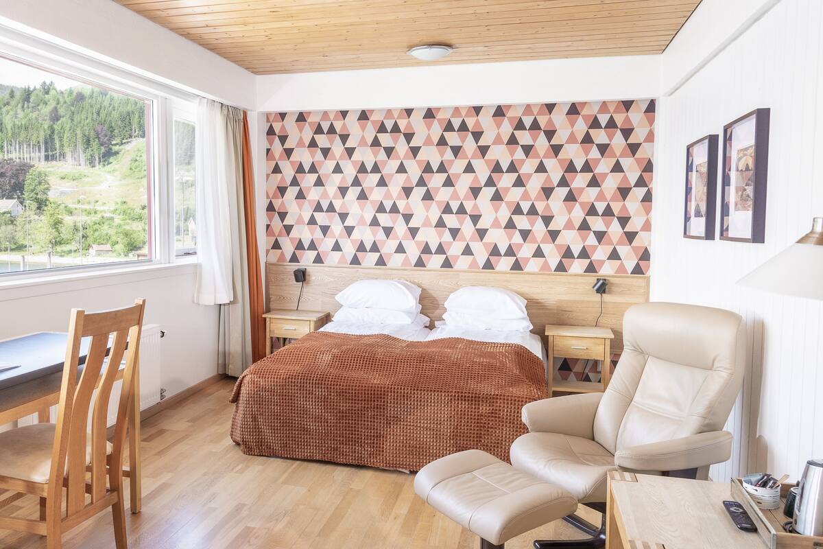 Una camera da letto con un letto, una scrivania, una sedia, un comodino e vista sull'esterno.