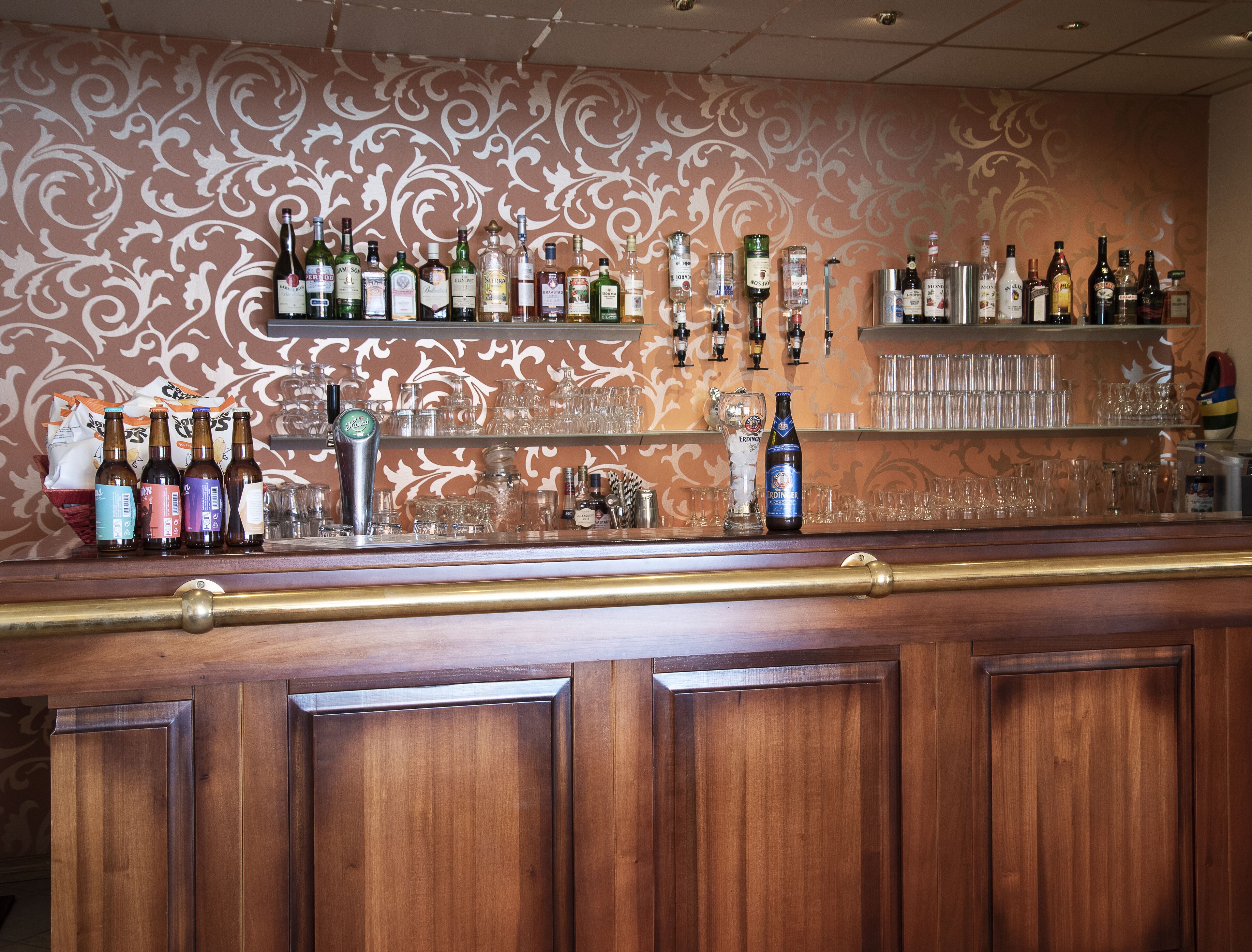 A bar area with shelves of various liquor bottles and glasses.