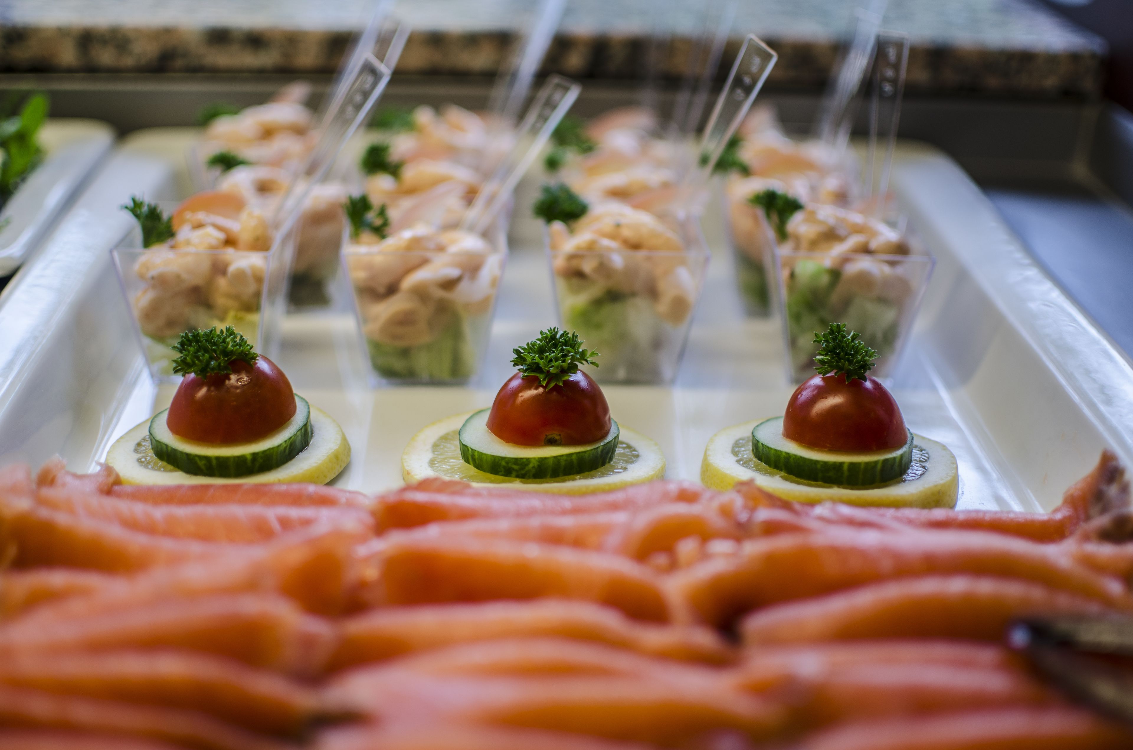 Un bufé con diferentes opciones de comida, entre ellas, aperitivos de salmón y vegetales.