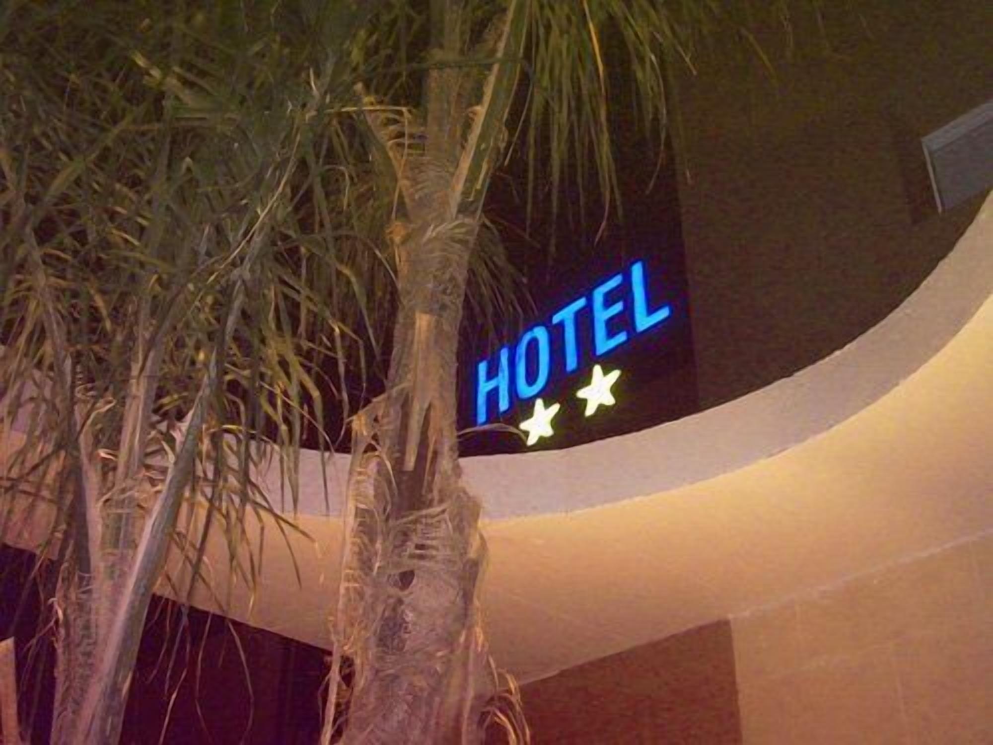 Un letrero de hotel con neón que dice 'HOTEL' y tres estrellas.