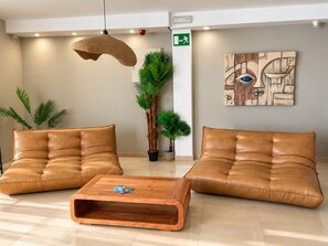 Un vestíbulo moderno con dos sofás de cuero, una mesa de centro de madera y un cuadro abstracto grande en la pared.