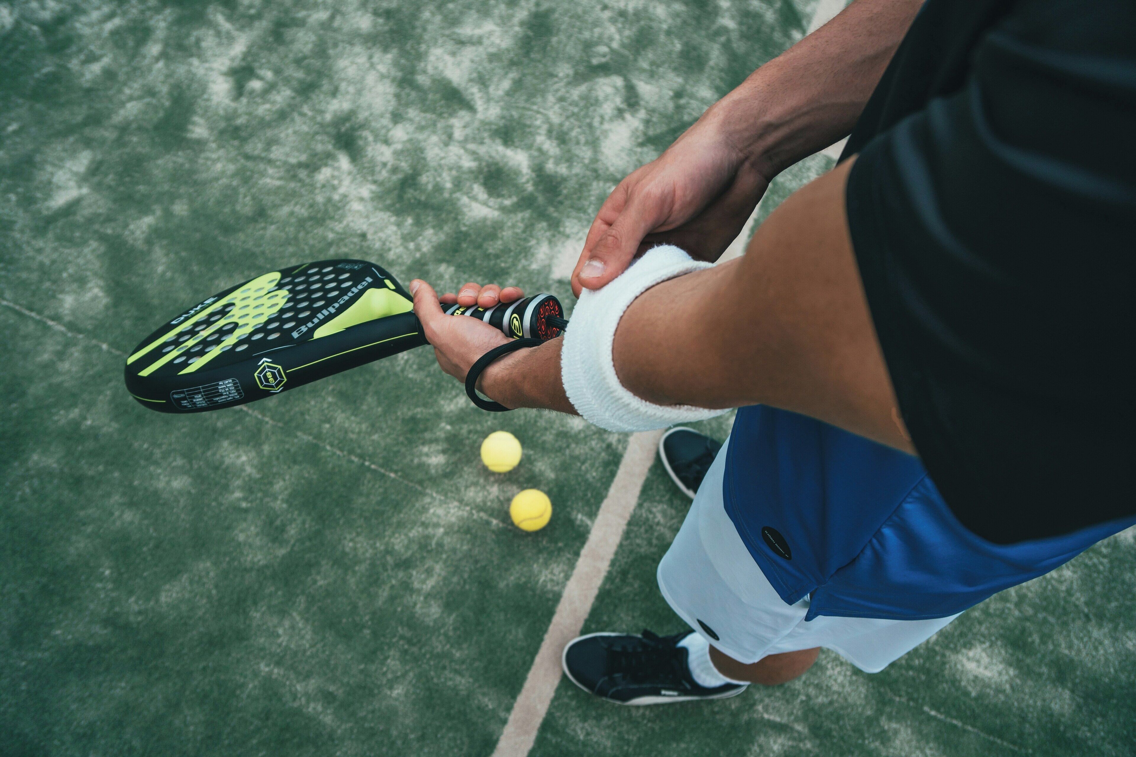 A tennis racket with a black and yellow design, held by a person wearing a white and blue outfit.