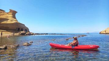 Una persona en kayak sobre aguas claras con formaciones rocosas a los lados.