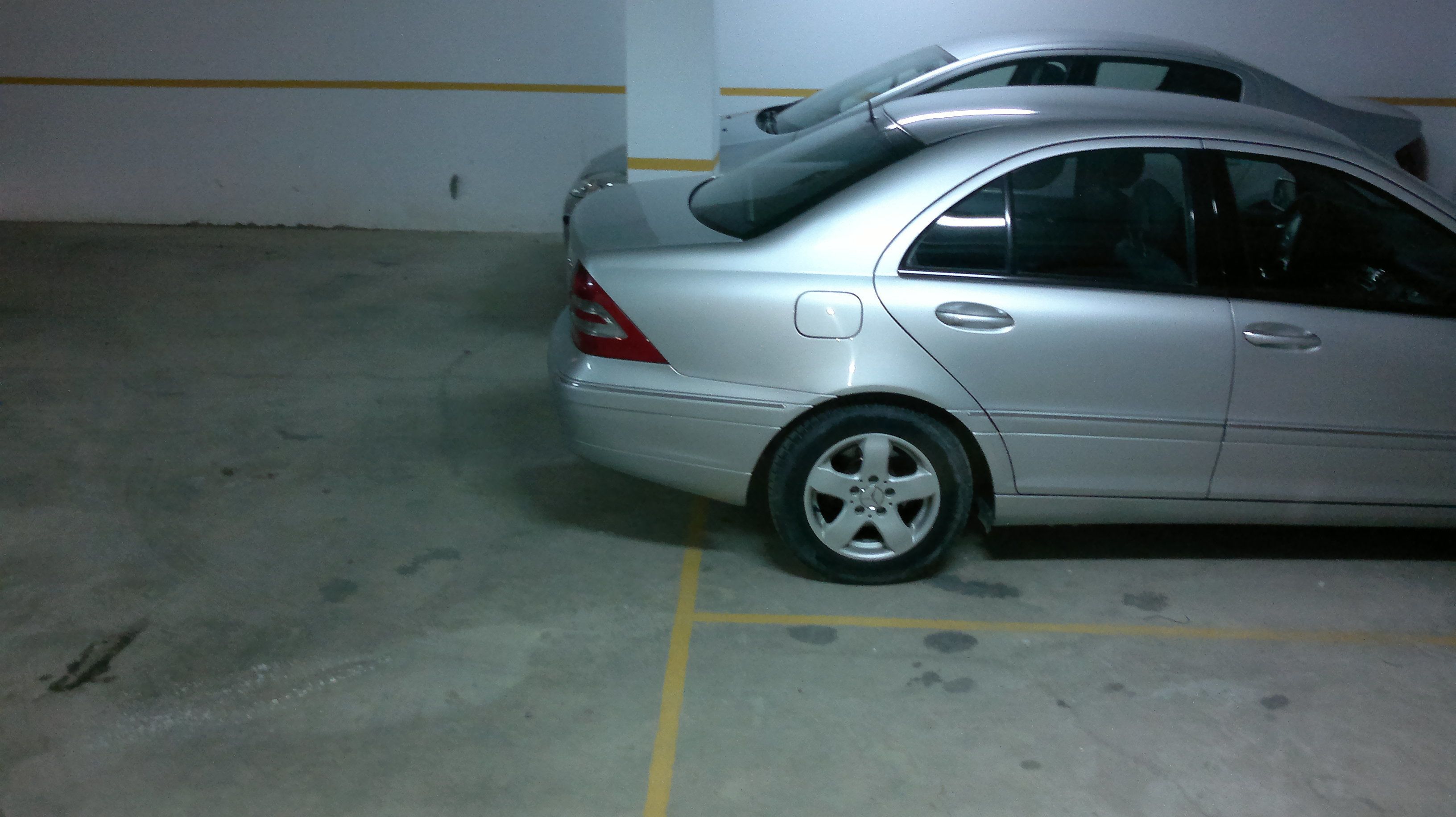 Een parkeergarage met een zilveren auto op een parkeerplaats.