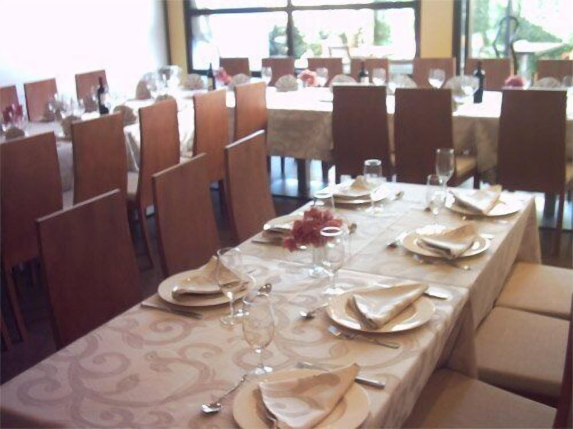 Un espace repas avec des tables dressées, des chaises et une vue sur l’extérieur grâce à de grandes fenêtres.