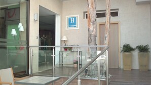 A hotel lobby with a glass railing, a reception desk, and a sign indicating a hotel named 'H'. - Hotel Playa Terreros by Blossom Hotels (Pulpi)