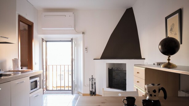 A modern kitchen with a large window, a fireplace, and a dining area with a table and chairs. - Italianway   - Bligny 39 (Milan)