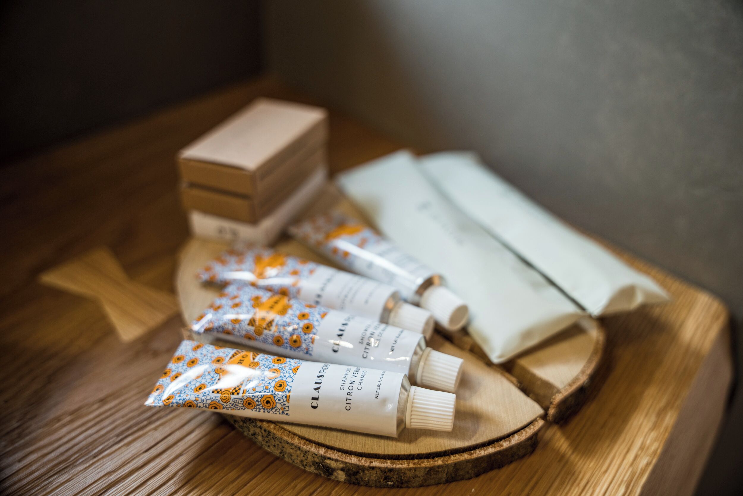 Ein Holztablett mit Pflegeprodukten, darunter eine Schachtel, Shampooflaschen und eine Lotionflasche.