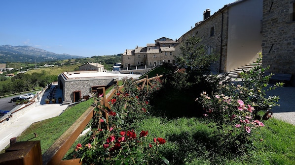 A stone building with a sloped roof, a staircase leading to a higher level, and a view of a hilly landscape in the background. - Borgotufi Albergo Diffuso (Castel del Giudice)