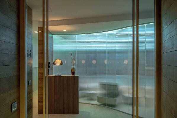 Un espace d’accueil moderne avec un comptoir de réception en bois, une lampe et un coin salon agrémenté d’un banc.