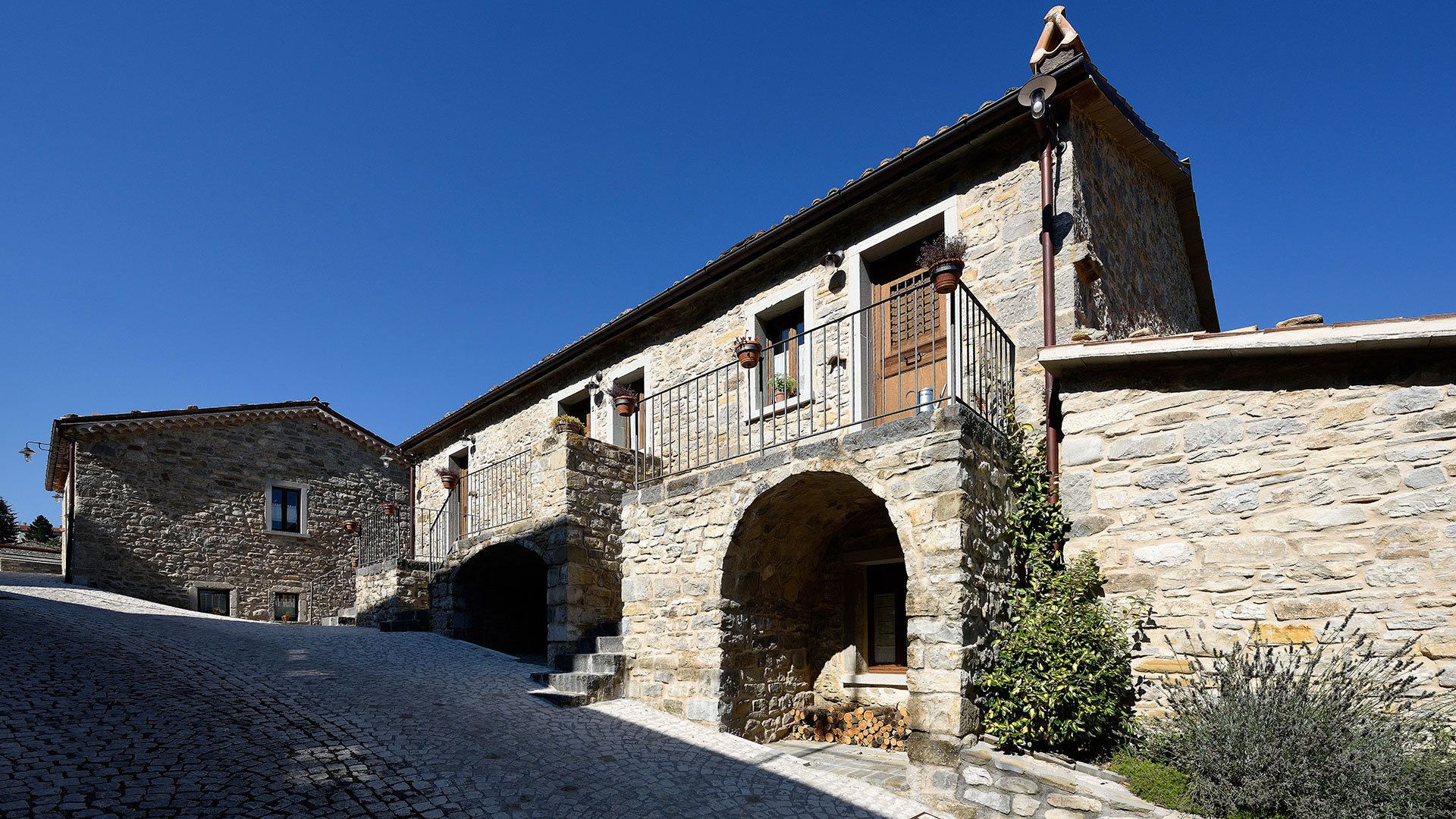 A stone building with a courtyard, a covered passageway, and a small garden area.