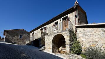A stone building with a courtyard, a covered passageway, and a small garden area.