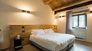 Una camera da letto con una testiera in legno, un letto con lenzuola bianche, un comodino con una lampada e una finestra con tende.