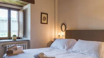 Una camera da letto con un letto grande, una finestra con tende, un termosifone e un quadro appeso al muro.