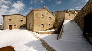 A stone building with multiple windows and a staircase leading up to a higher level. - Borgotufi Albergo Diffuso (Castel del Giudice)