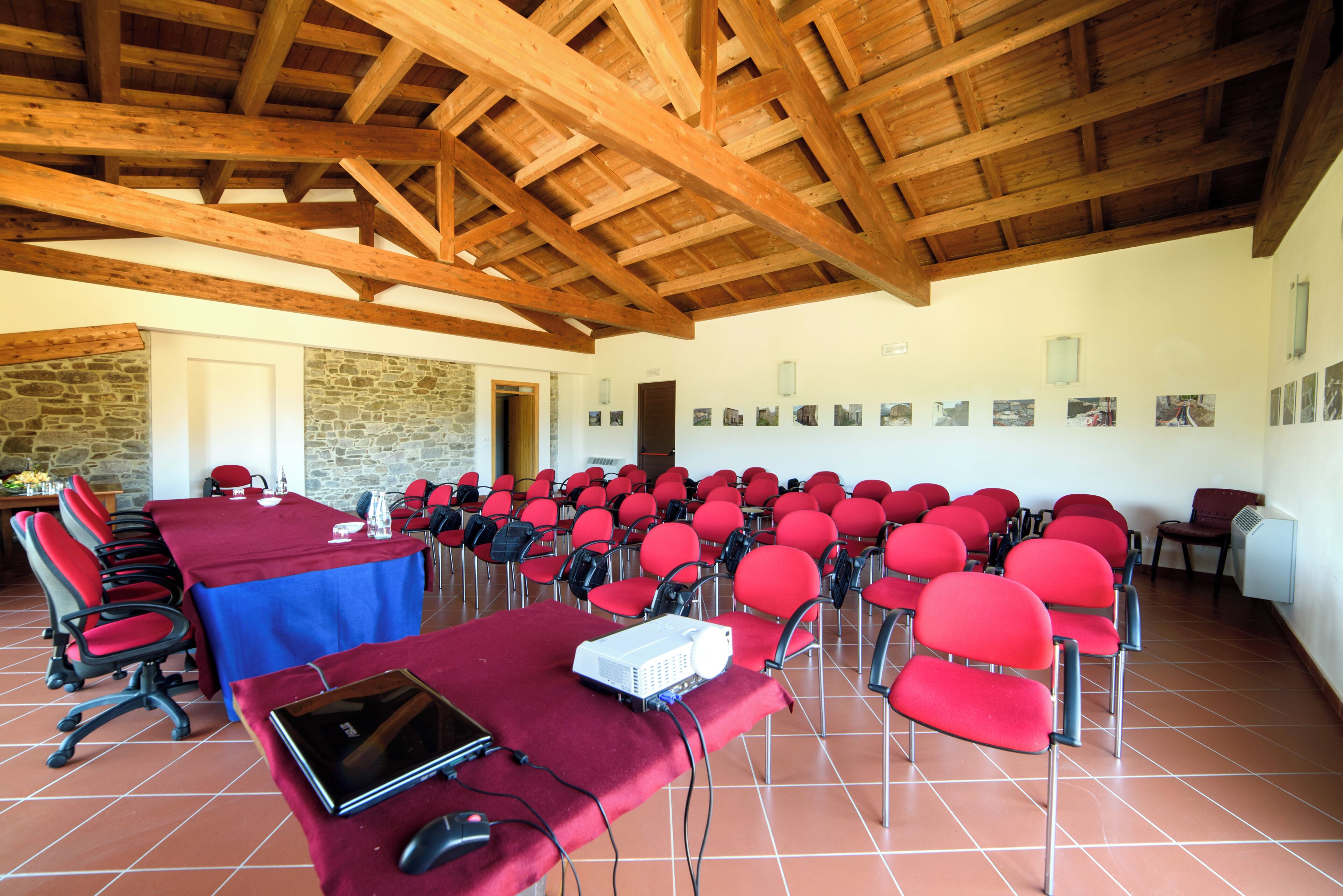 Une salle de conférence avec une longue table, des chaises rouges et un projecteur posé sur une table.
