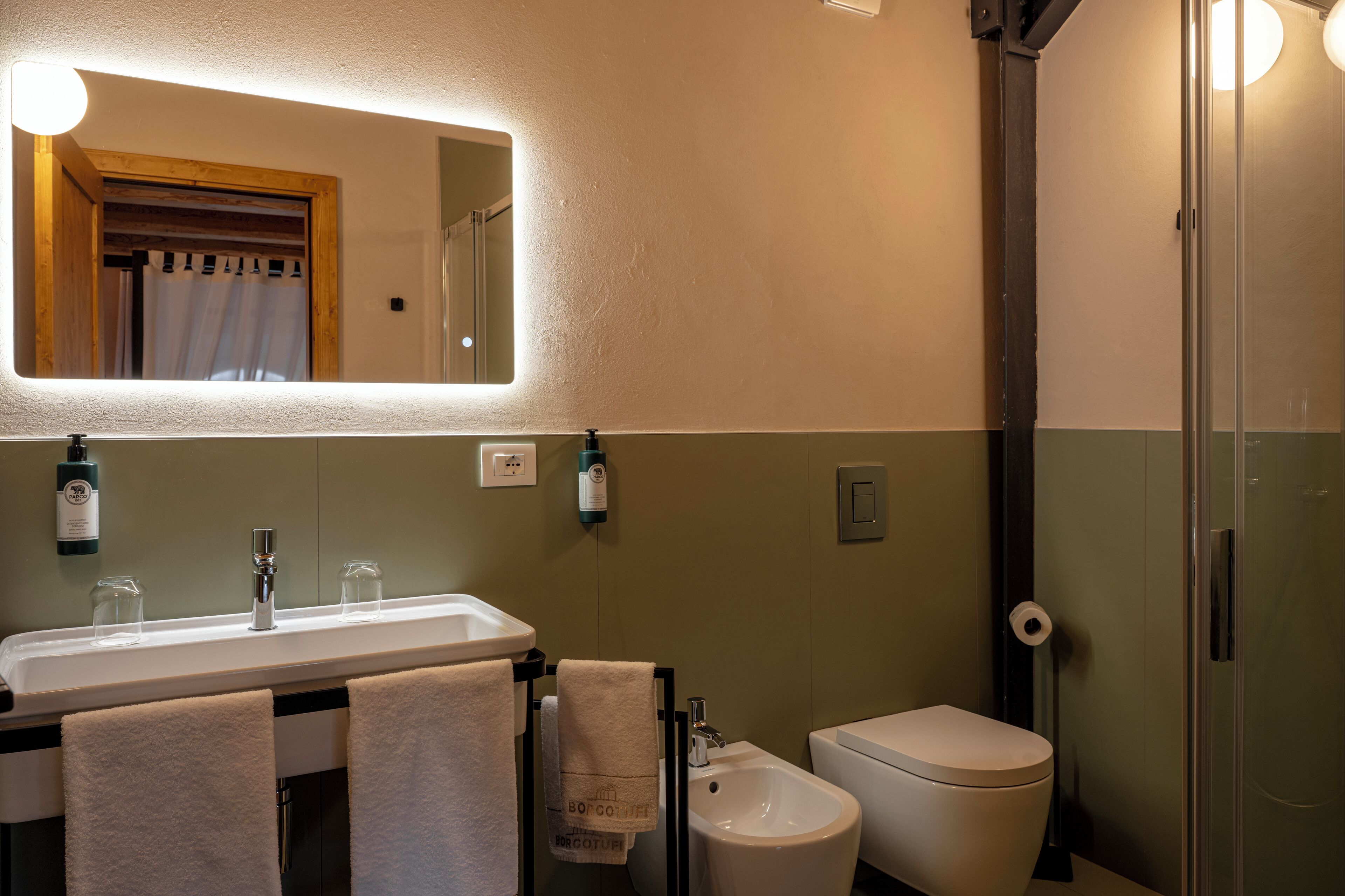 Une salle de bain équipée d’un lavabo, d’un miroir, d’un porte-serviettes, de toilettes et d’une douche.