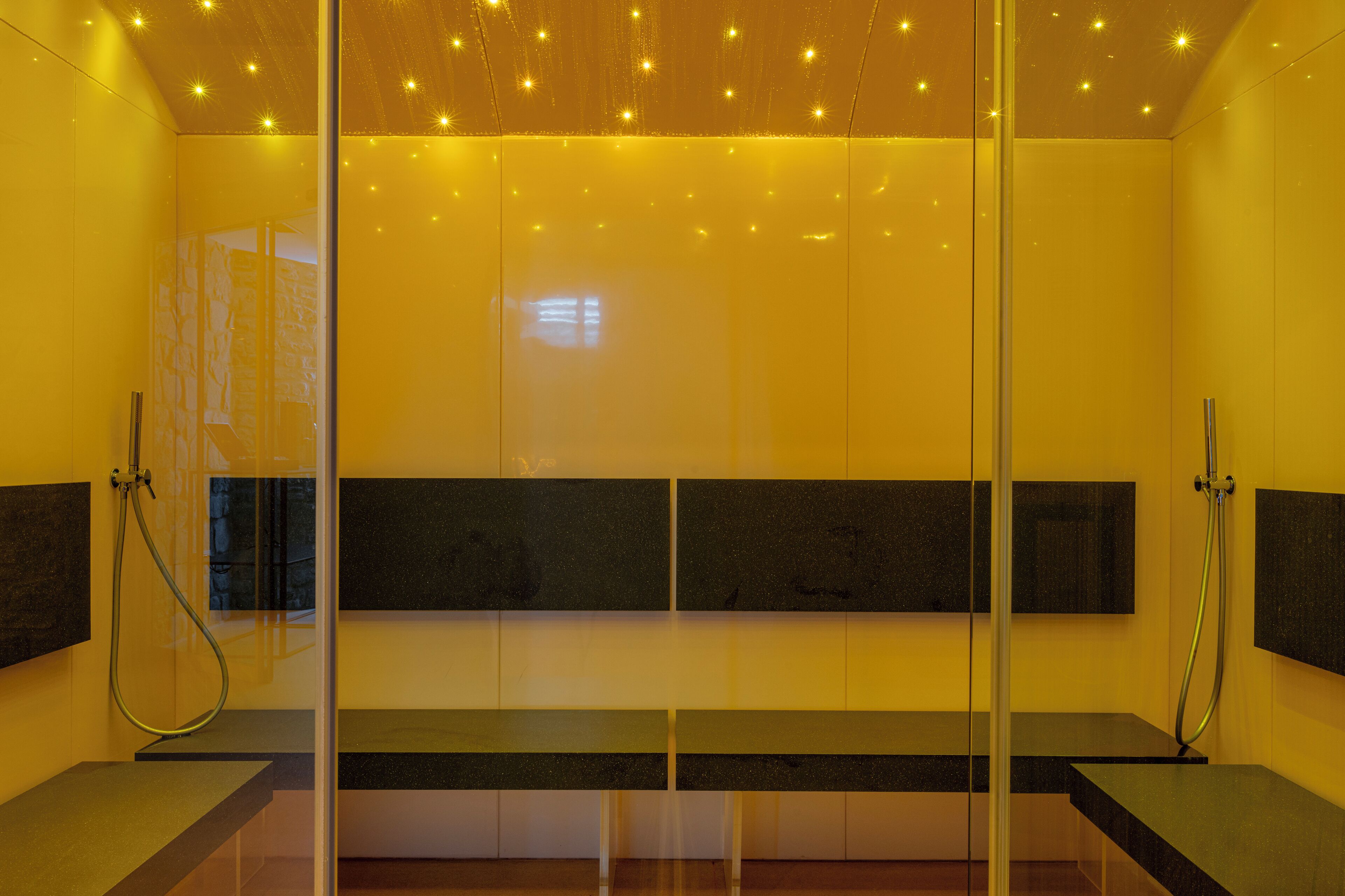 A modern bathroom with a glass partition, a bench, and a shower area.