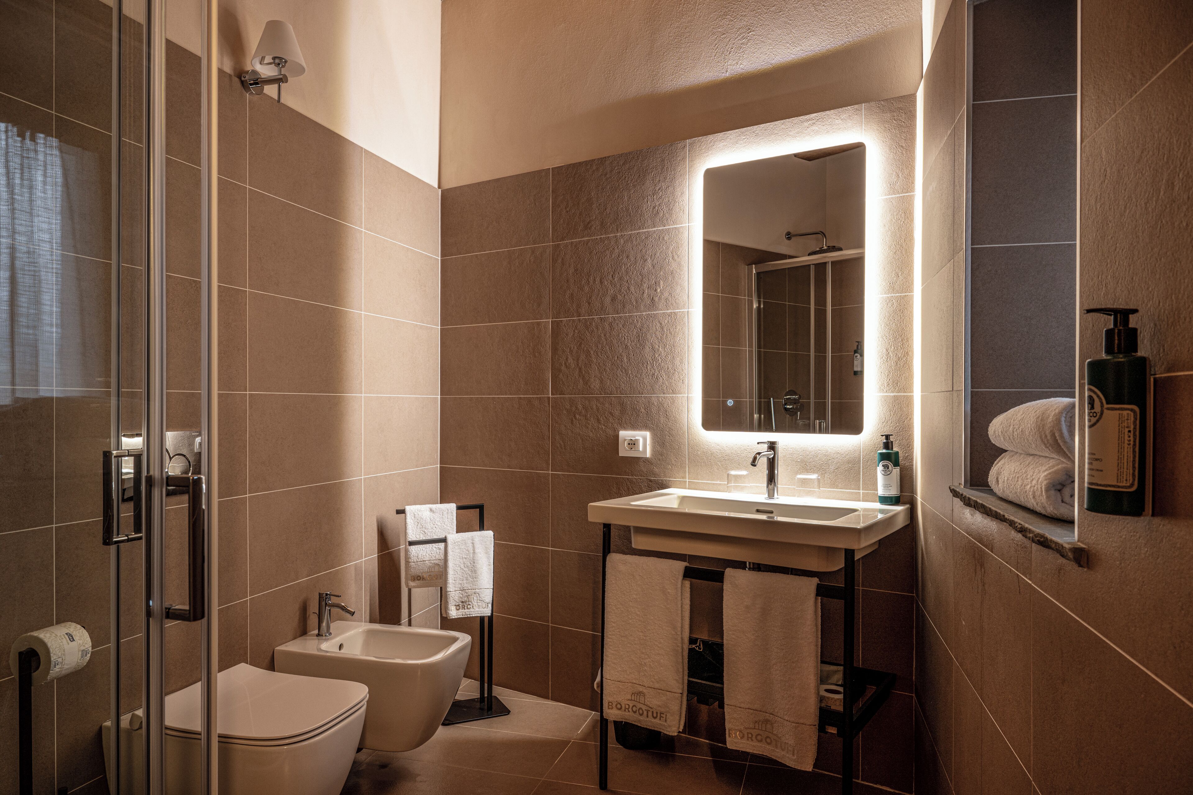 Un baño moderno con cabina de ducha de vidrio, un inodoro independiente y un lavabo con espejo.
