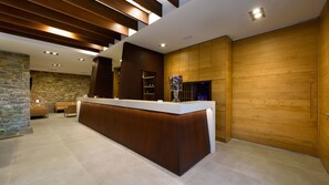 A modern reception area with a wooden reception desk, stone wall, and a seating area with sofas. - Borgotufi Albergo Diffuso (Castel del Giudice)