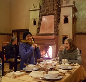 Un comedor con chimenea, mesa de madera y sillas.