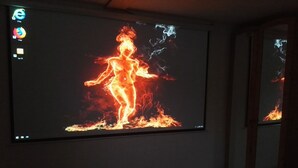 A room with a large screen displaying a fiery image. - Ferienwohnungen nähe Badesee (Bergneustadt)