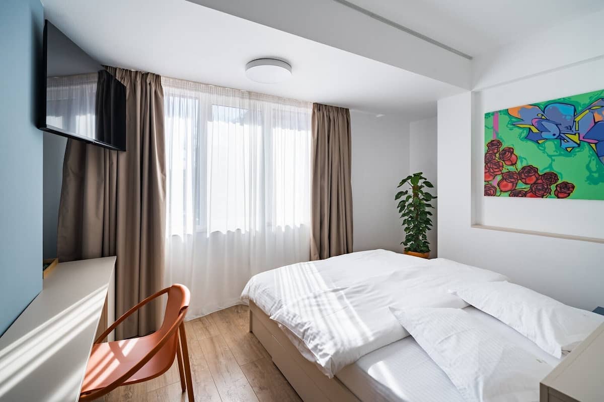 Een moderne slaapkamer met een bed, een stoel, een televisie en een schilderij.