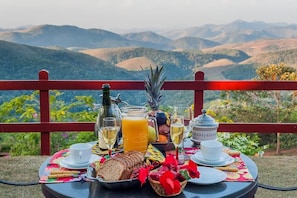 Una mesa preparada con alimentos para el desayuno y una vista panorámica de montañas.