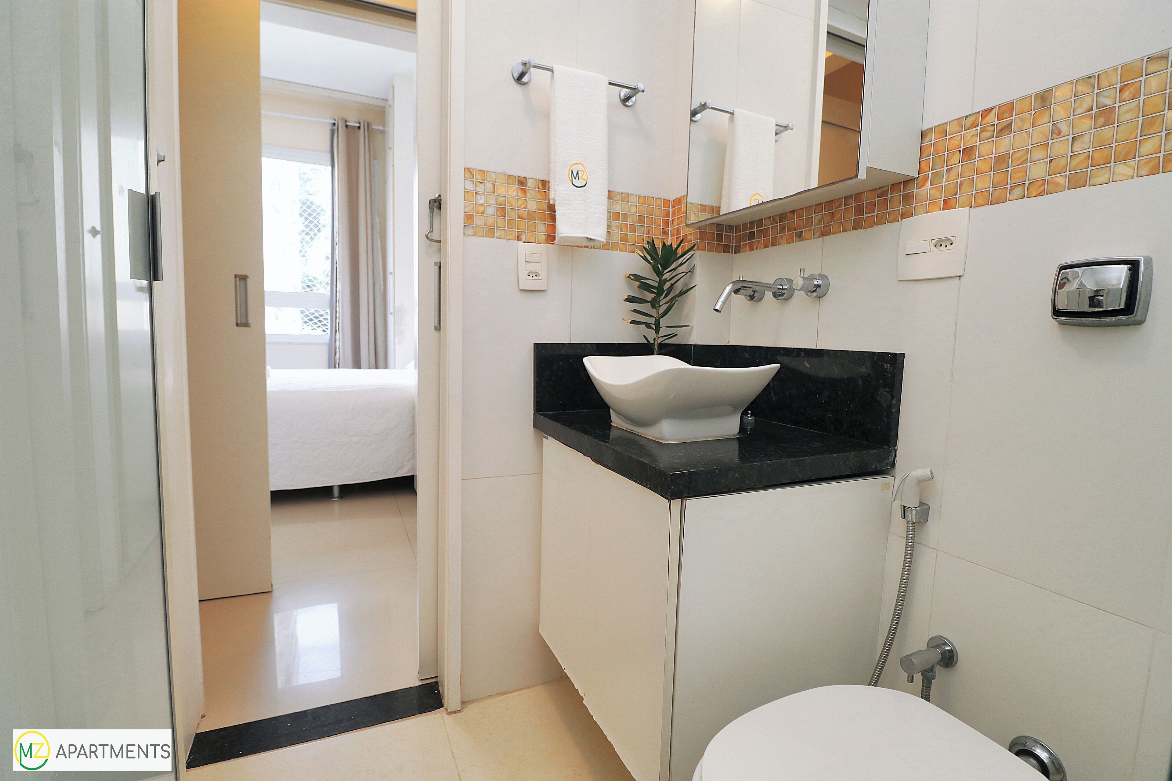 Ein modernes Badezimmer mit einem weißen Waschbecken, einer schwarzen Arbeitsplatte und einer Dusche mit Duschbrause.