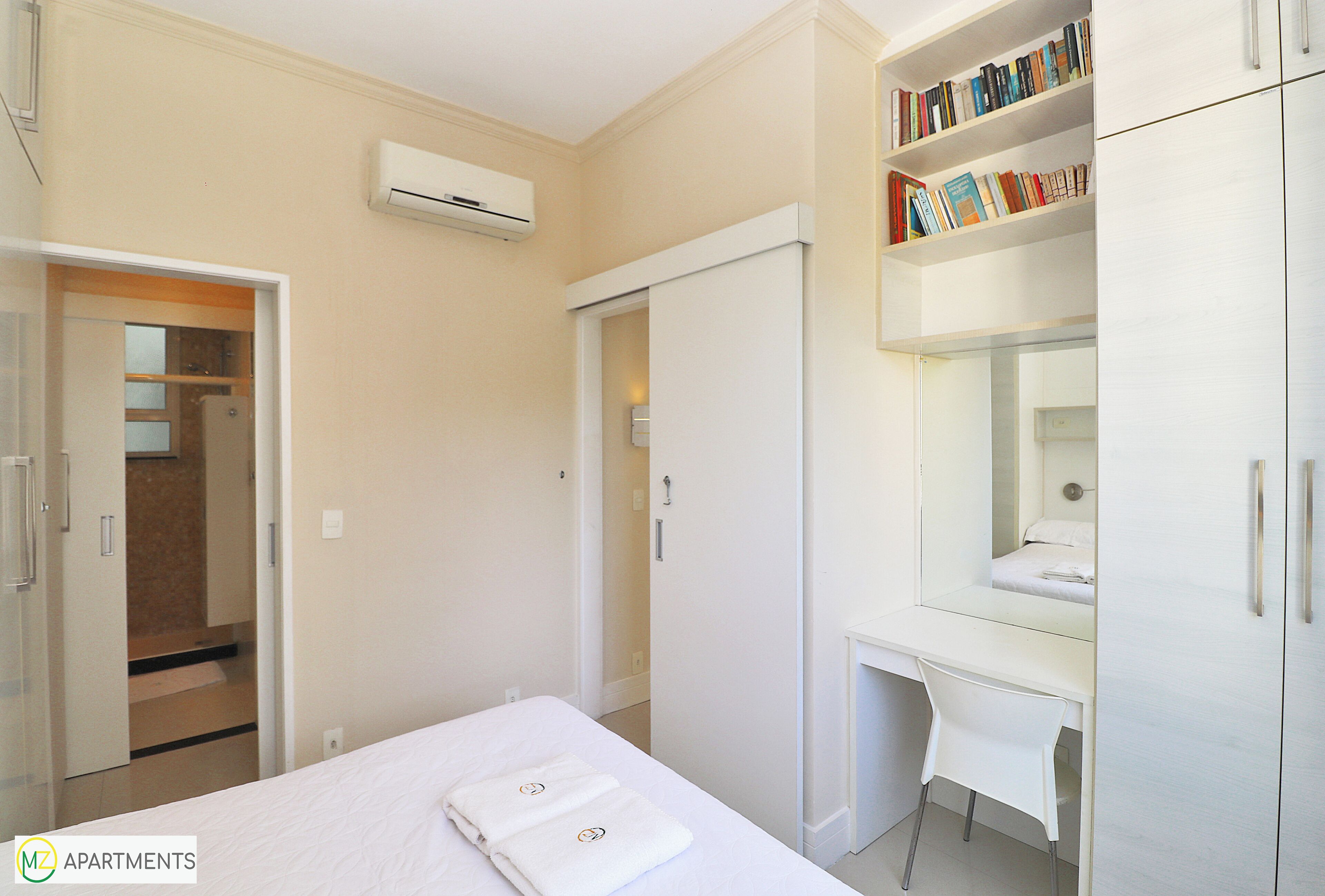 A bedroom with a bed, a desk, a wardrobe, and a bookshelf.