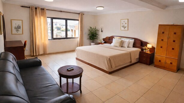 Una habitación de hotel con cama, escritorio, sofá, una mesita y armario.