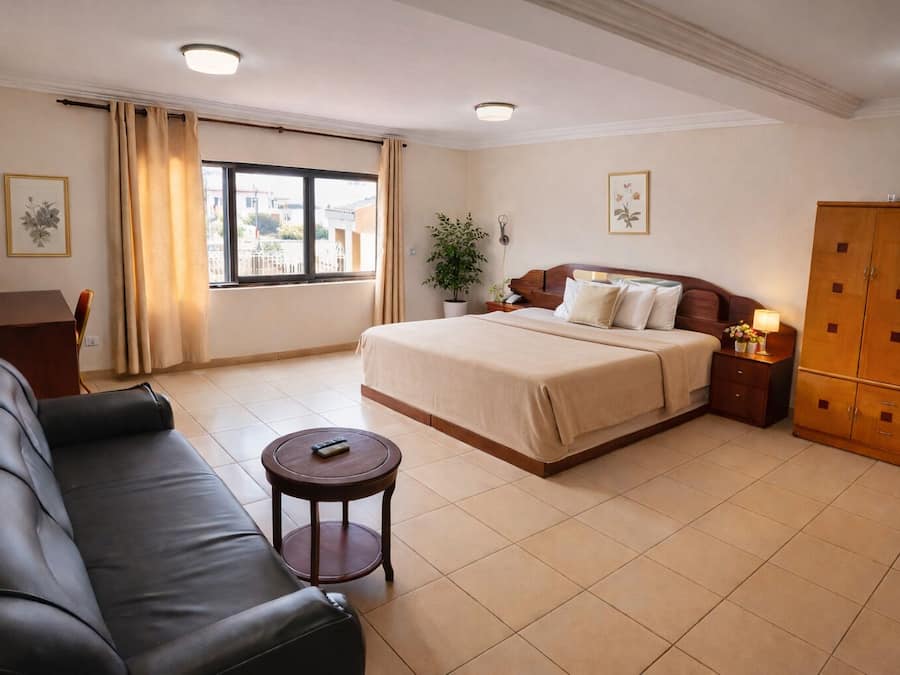 Una habitación de hotel con cama, escritorio, sofá, una mesita y armario.