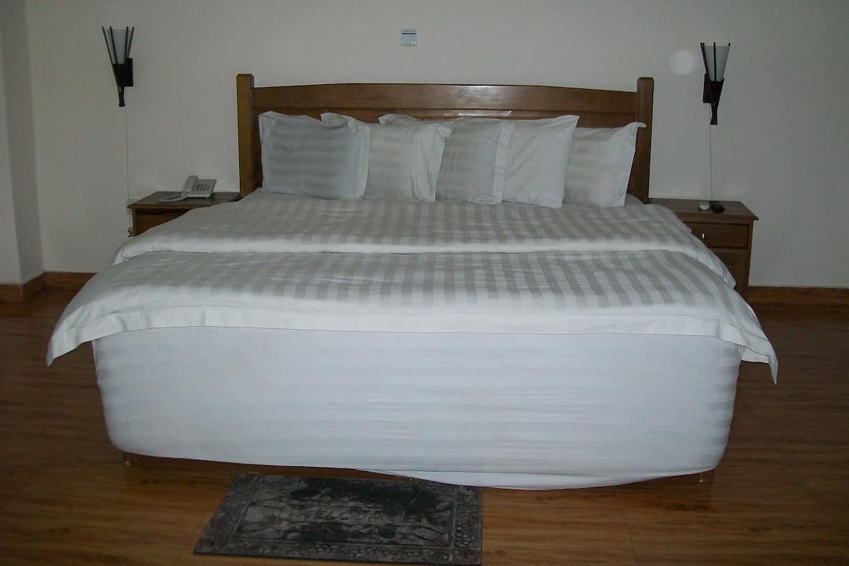 A large bed with a wooden headboard, white bedding, and two bedside tables with lamps.