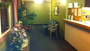 A reception area with a desk, chairs, a plant, and a wall with a 'No Smoking' sign.