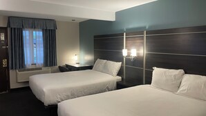 A hotel room with two beds, a desk, a chair, a window with curtains, and a wall-mounted light fixture. - Landmark Inn (Osawatomie)