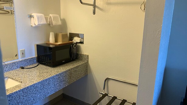 A small kitchenette with a microwave, a sink, and a towel rack.
