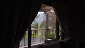 Una habitación con vistas a un balcón, una cama y una ventana con cortinas.