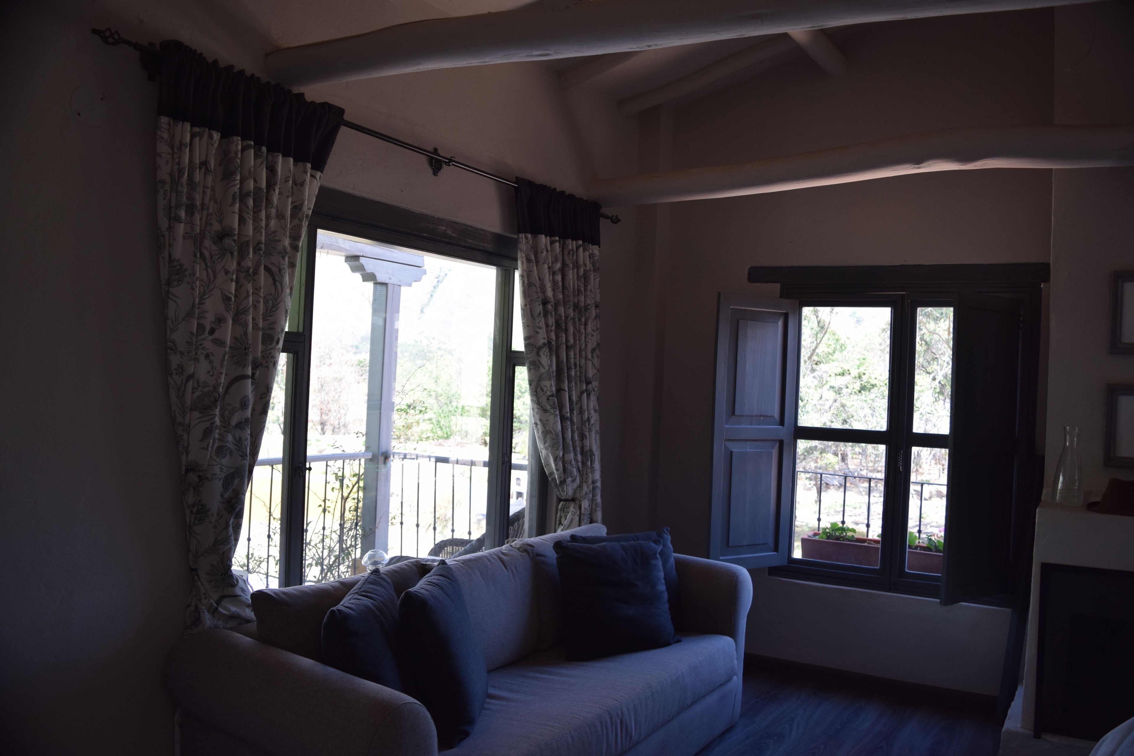A living room with a sofa, two windows with curtains, and a fireplace.