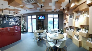 A modern bar area with a red counter, white chairs, and a Christmas tree. - Wine Hotel (Chisinau)