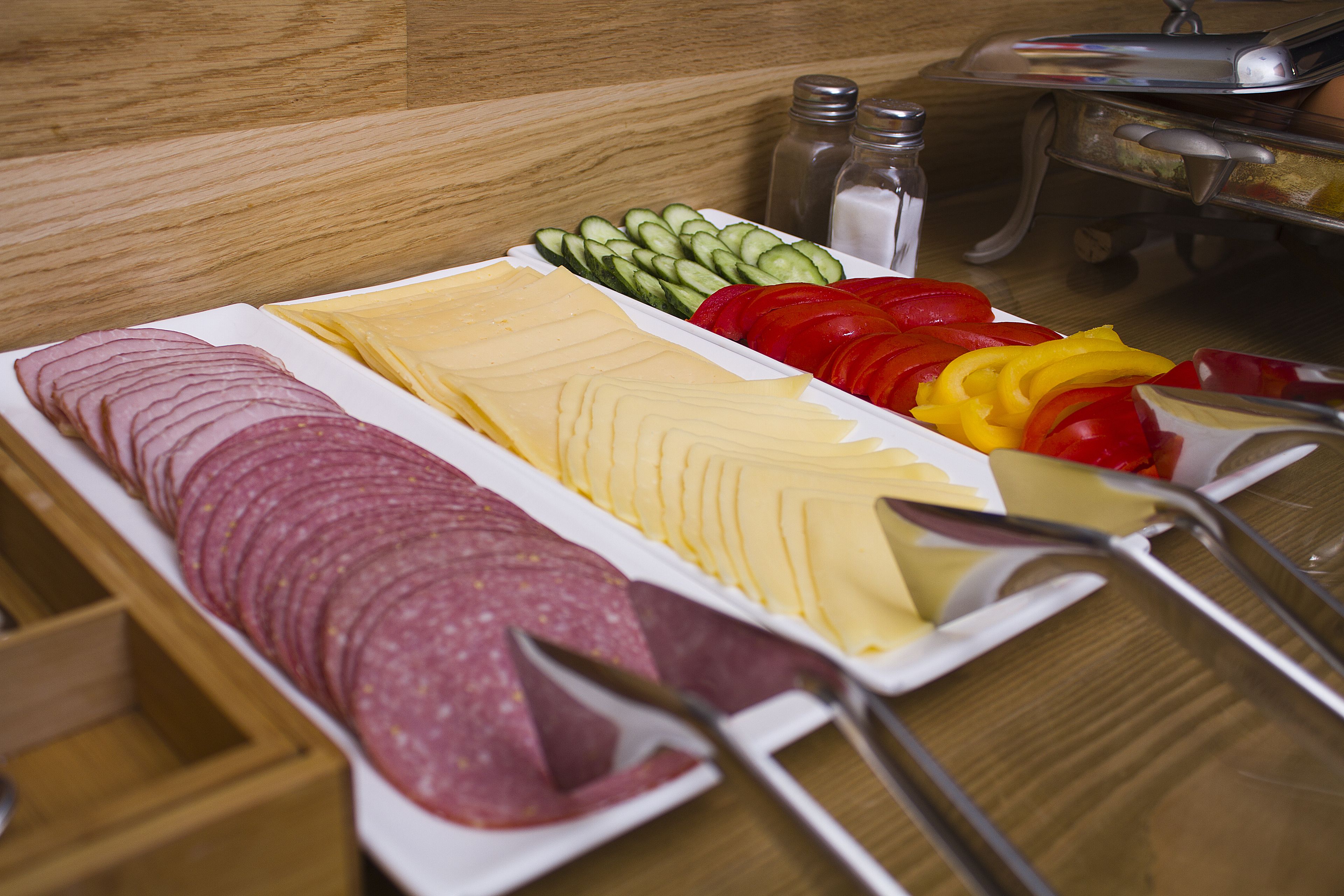 A charcuterie board with sliced meats, cheeses, and vegetables.
