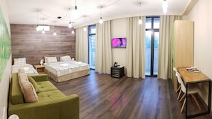 A modern hotel room with a wooden accent wall, a green sofa, a bed with a checkered duvet, a wooden desk, and a TV on the wall. - Wine Hotel (Chisinau)