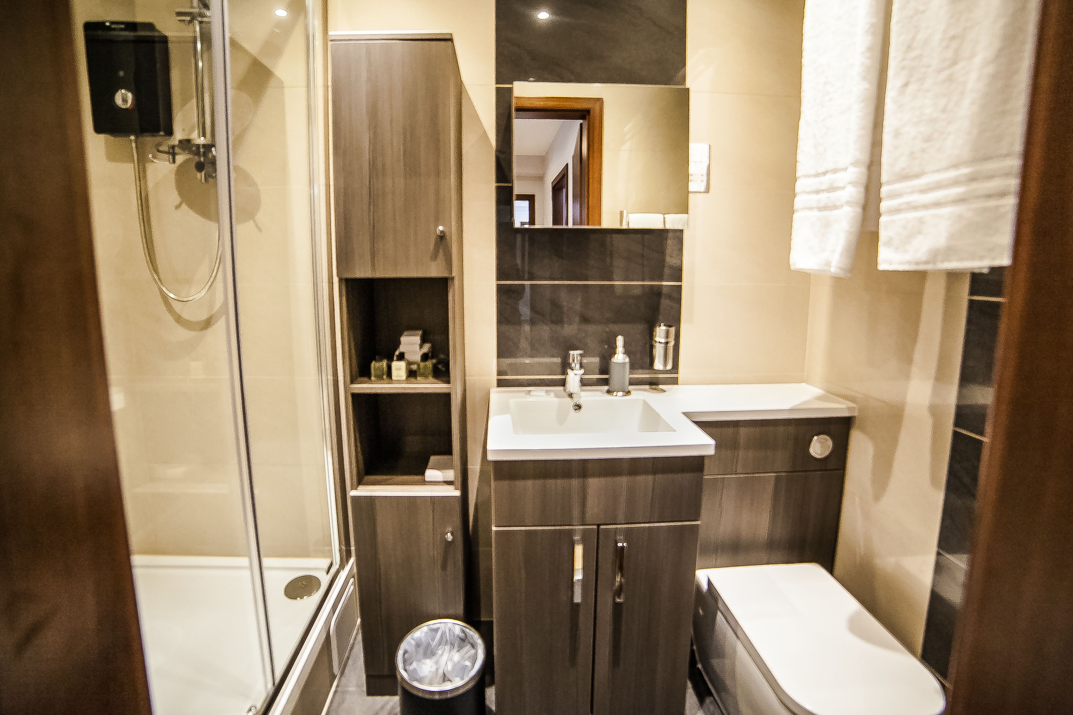 A modern bathroom with a glass-enclosed shower, a sink, and a toilet.