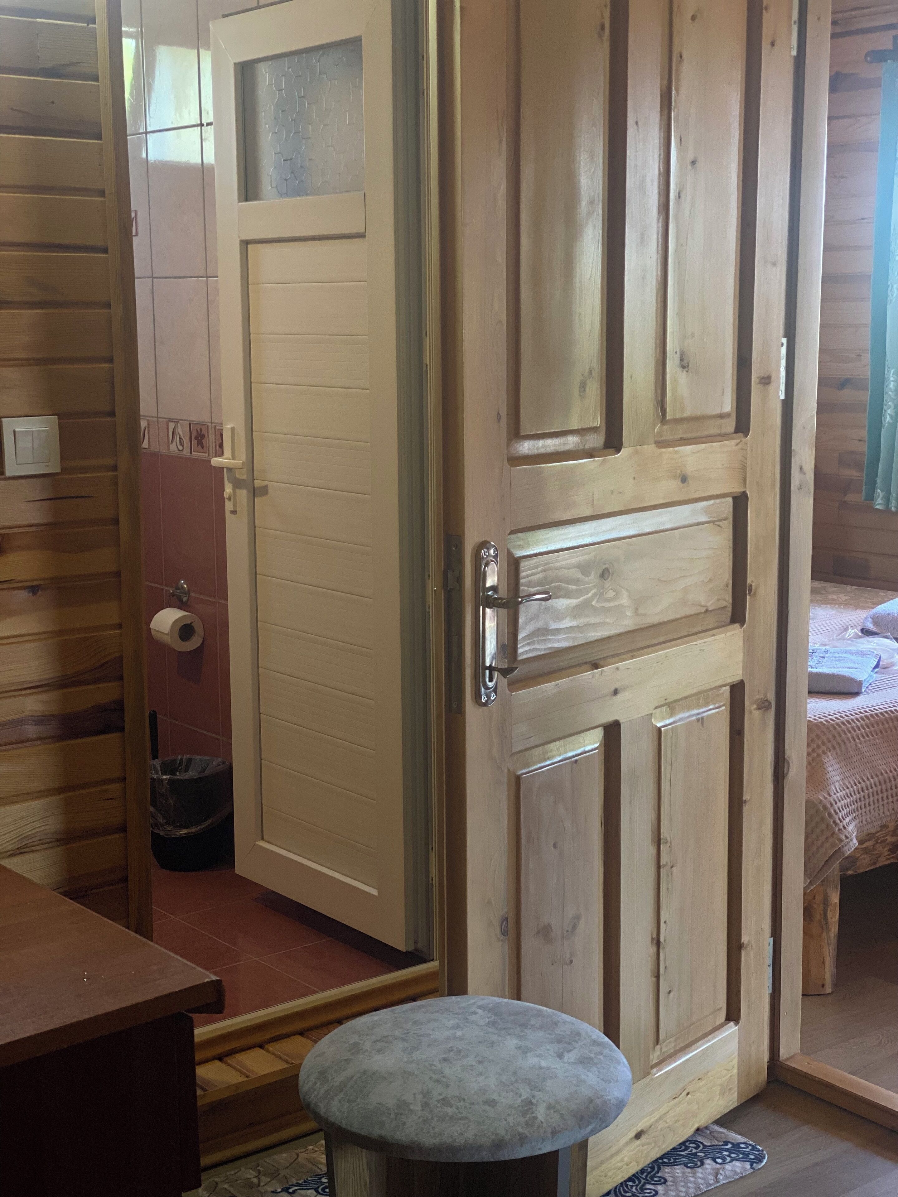 Eine Holztür mit Griff, ein kleiner Hocker und ein Handtuch auf einem Bett.